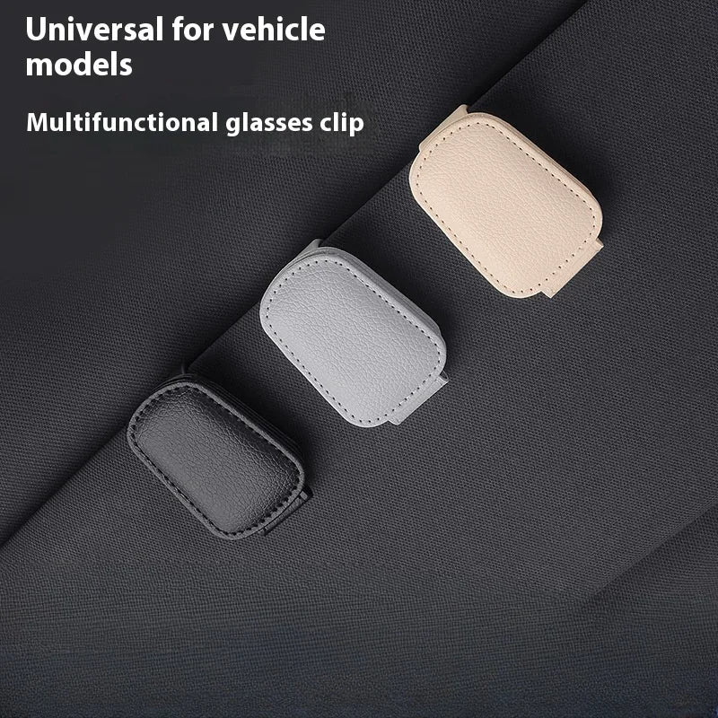 Multifunctional glasses clip in black, gray, and beige on a dark fabric background.